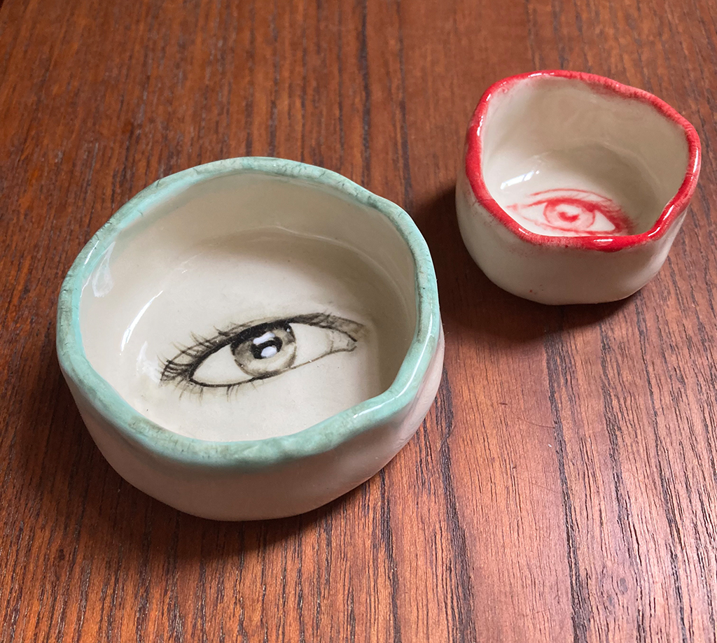 two ceramic bowls with eyes painted in their centers
