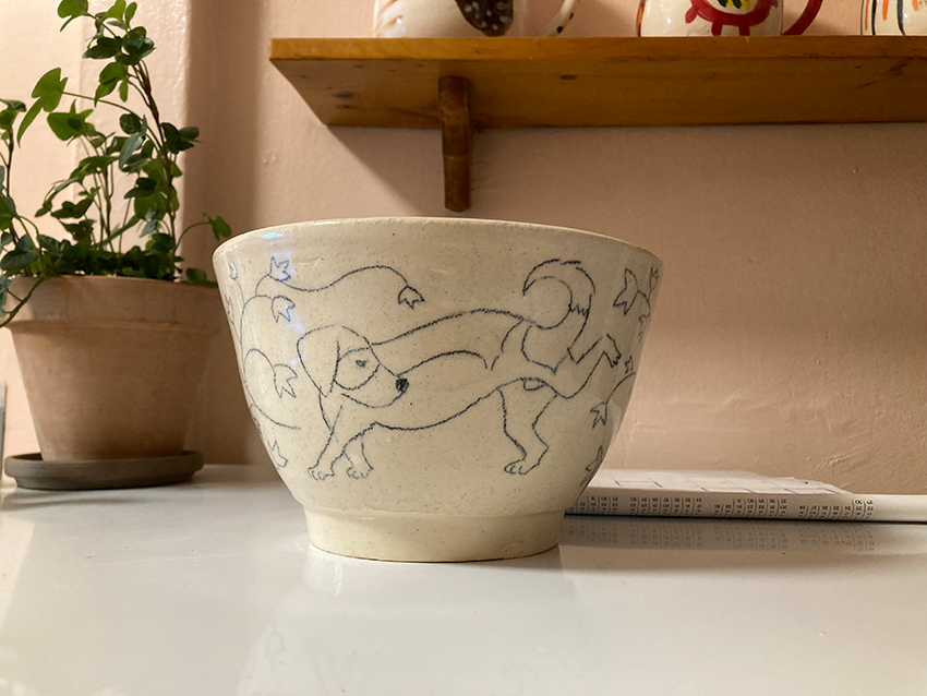 back of flowerpot with drawing of hound dog urinating on ivy leaves